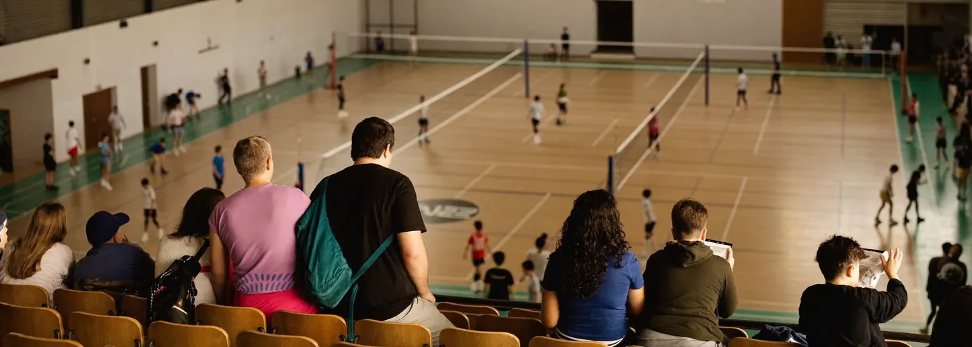 Parents watching a youth volleyball tournament from the bleachers